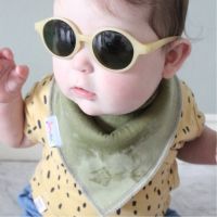 Dotty Fish Olivgrünes Babylätzchen, getragen von einem kleinen Jungen mit Sonnenbrille.