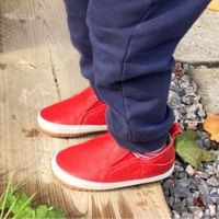 Kleinkind trägt draußen rote Schuhe mit Gummisohle