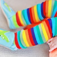 Baby trägt regenbogengestreifte Stulpen von Dotty Fish