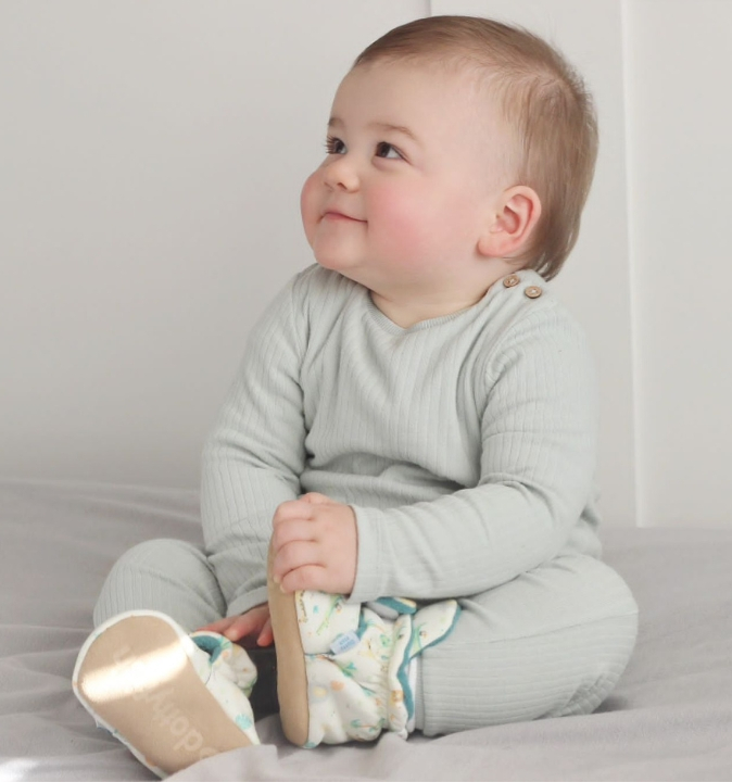 Babyjunge trägt Baumwoll-Schühchen von Dotty Fish im Safari-Design