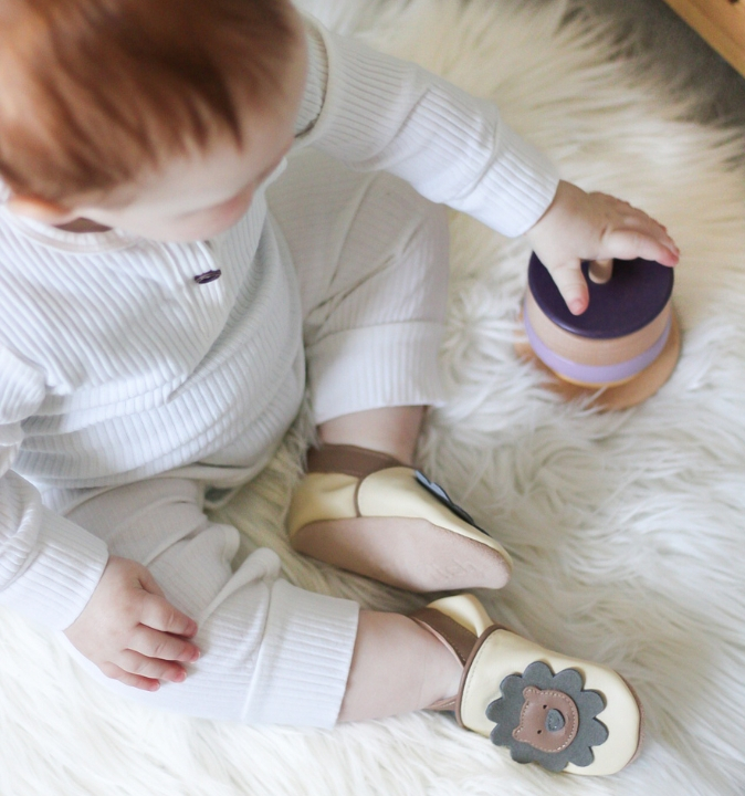 Babyjunge trägt Löwenschuhe von Dotty Fish