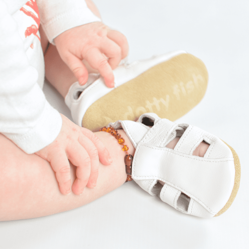 Baby sitting wearing white leather baby sandals form Dotty Fish with soft soles