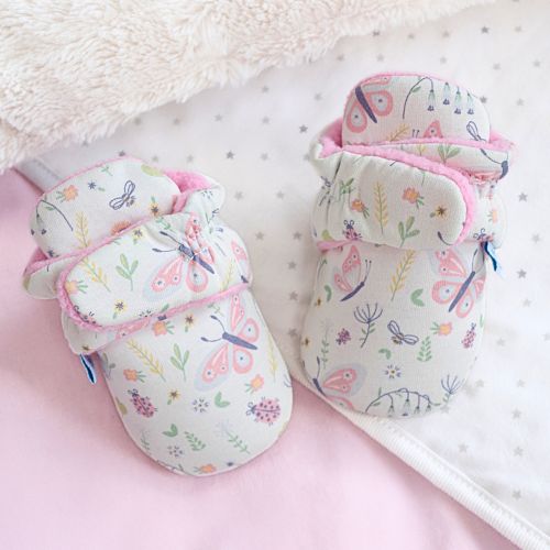 Cream baby booties with floral pattern, sitting on baby blanket.