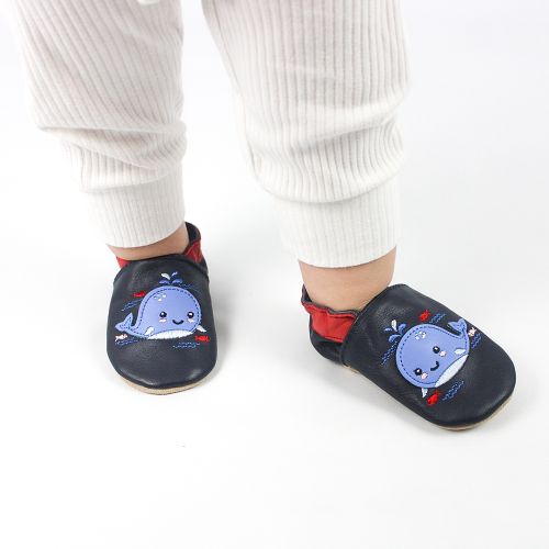 Blue leather baby shoes with whale design worn by toddler while walking inside