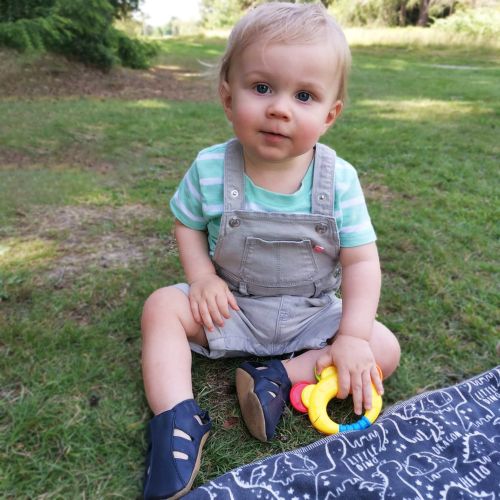 Kleiner Junge in marineblauen Dotty Fish first walker Barfußsandalen, der draußen spielt.