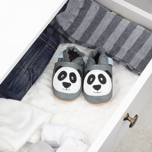 Graue Krabbelschuhe aus Leder mit Pandamotiv, in einer Schublade mit Babykleidung.