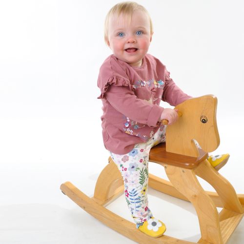 Little girl on rocking horse wearing yellow daisy soft leather baby shoes from Dotty Fish 