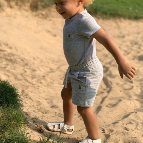 Toddler playing in the sand while wearing cream leather sandals with soft soles form Dotty Fish 
