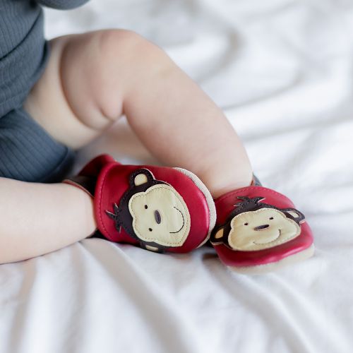 Baby wearing red leather baby shoes with cheeky monkey design from Dotty Fish 