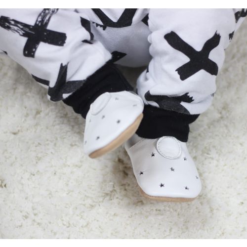 Tiny baby wearing white leather baby shoes with simple cut out star design by Dotty Fish 