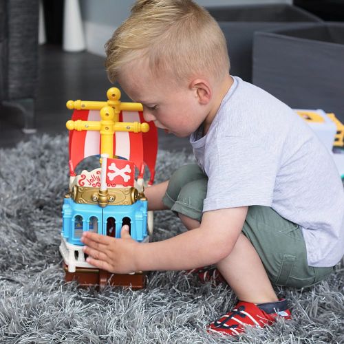 Little boy playing with toys while wearing red and navy nautical anchor soft leather slippers from Dotty Fish 