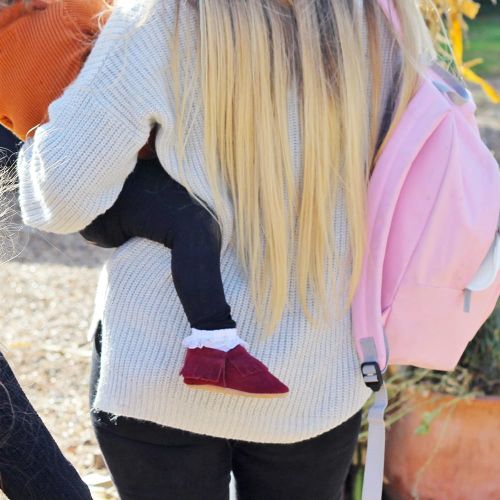 Mother carrying baby who is wearing berry red suede baby moccasins by Dotty Fish 