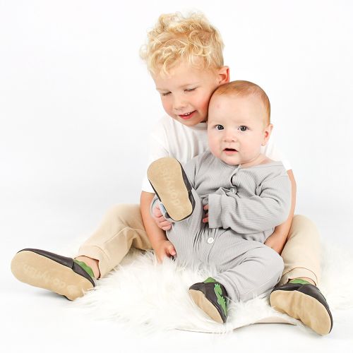 Ein Baby und ein Kleinkind sitzen zusammen und tragen braune Dotty Fish Dinosaurierschuhe.