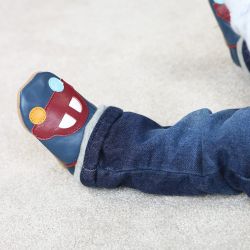 Navy blue baby shoes with red car design worn by little baby while sitting on the floor