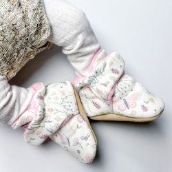 Baby-Mädchen trägt cremefarbene Dotty Fish-Schuhe aus Baumwolle mit rosa Fleece-Futter und Schmetterlings- und Bienenmuster.