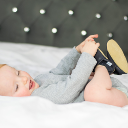 Baby playing with his feet while wearing navy blue soft leather baby shoes from Dotty Fish 