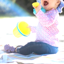 Baby playing in the sand while wearing purple flower sandals from Dotty Fish 