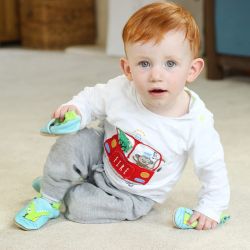 Kleiner Junge sitzt auf dem Boden und trägt hellblaue Dotty Fish-Krokodilschuhe.