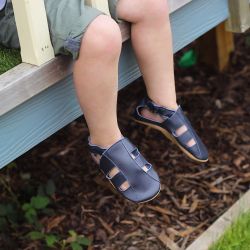 Kleinkind trägt navy Leder Dotty Fish erste Walker barfuß Sandalen.