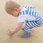 Toddler wearing Dotty Fish soft leather sandals while walking on the beach