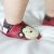 Kleinkind mit roten Dotty Fish Schuhen mit braunem und cremefarbenem Affenmuster.