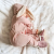 Baby in rosa Wildlederpantoffeln und einem Hasen-Strampelanzug.