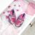 Lila und rosa Krabbelschuhe mit Schmetterlingen in einer Schublade mit Babykleidung.