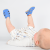 Liegender kleiner Junge mit blauen Dotty Fish Barfußsandalen aus Leder für die ersten Schritte.