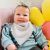 Babymädchen trägt ein hellgraues Bandana-Lätzchen aus Baumwolle von Dotty Fish.